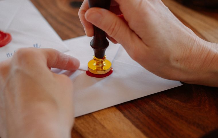 Hand reikt een envelop aan met waszegelstempel — veilig en vertrouwelijk